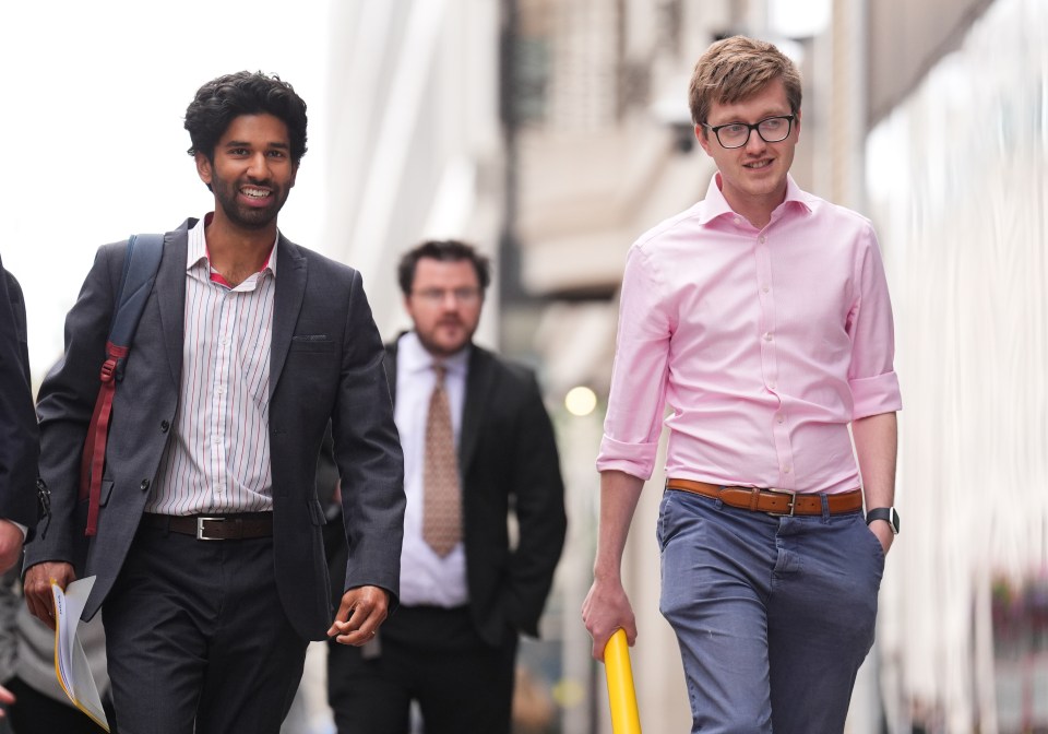 a man in a pink shirt is walking with two other men