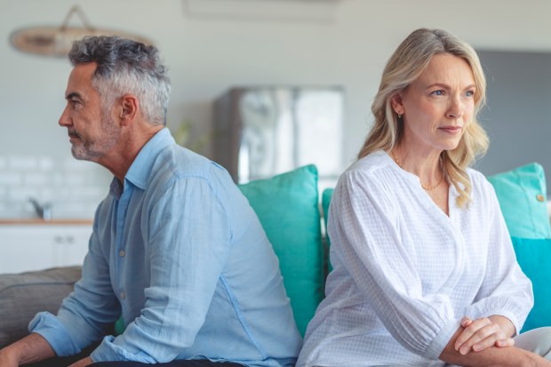 a man and a woman sit back to back on a couch