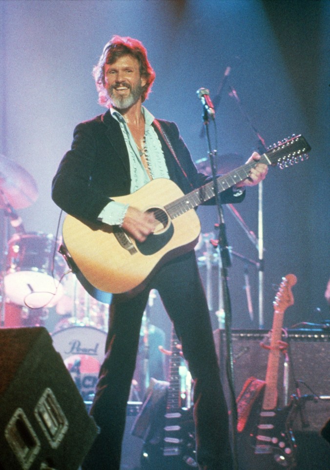 a man playing a guitar on a stage with a pearl guitar in the background