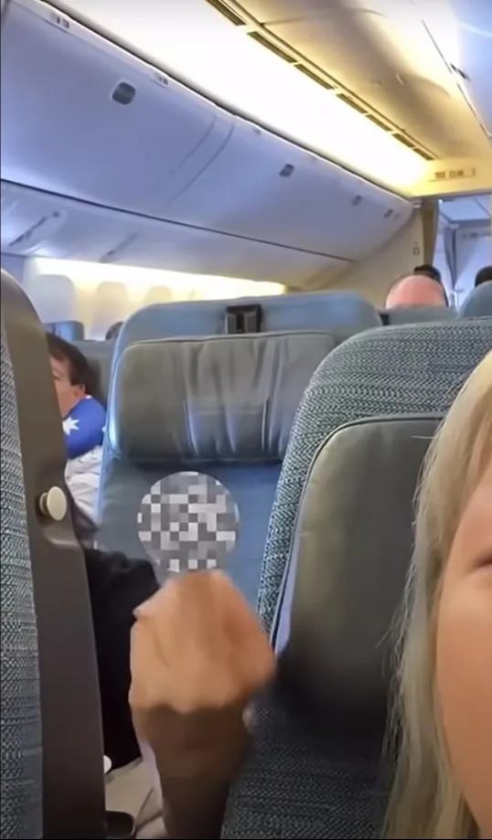 a person sitting on an airplane with the word exit on the ceiling