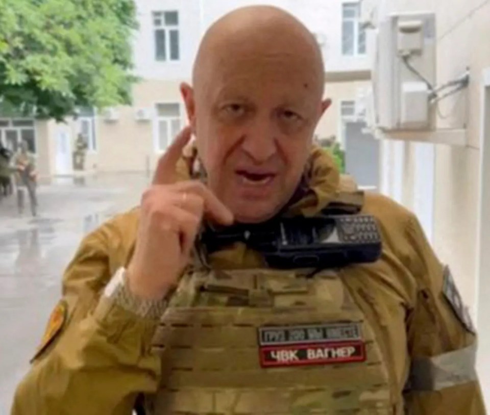 a bald man in a military uniform is talking on a cell phone .