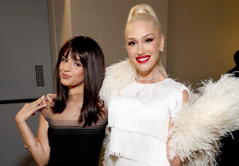 two women posing for a picture with one wearing a white feathered cape