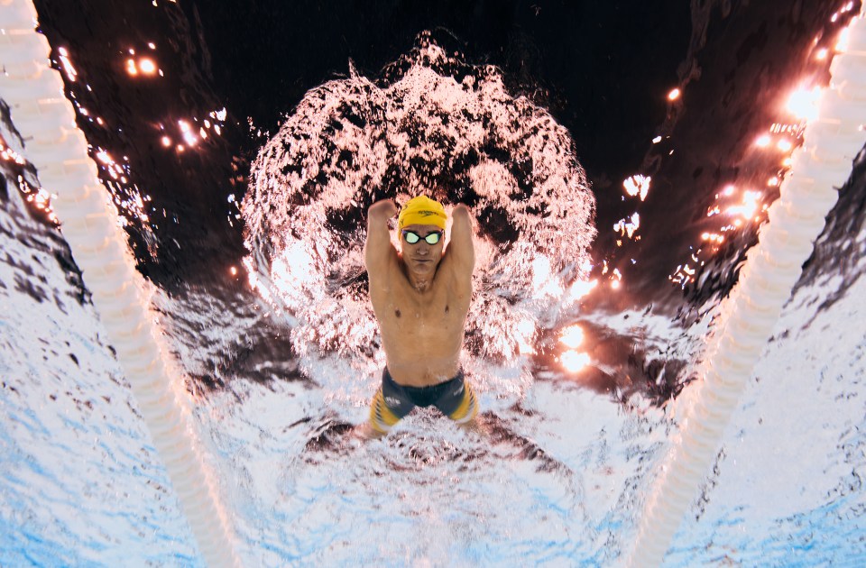 a man wearing a speedo swim cap is swimming in a pool