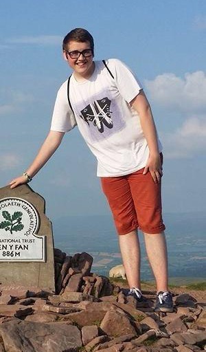 a young man is standing on top of a rocky hill .