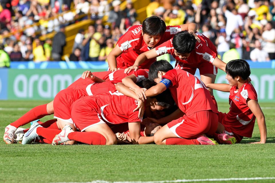 a group of soccer players huddle together on the field