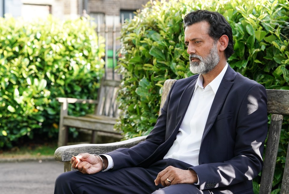 a man in a suit sits on a wooden bench