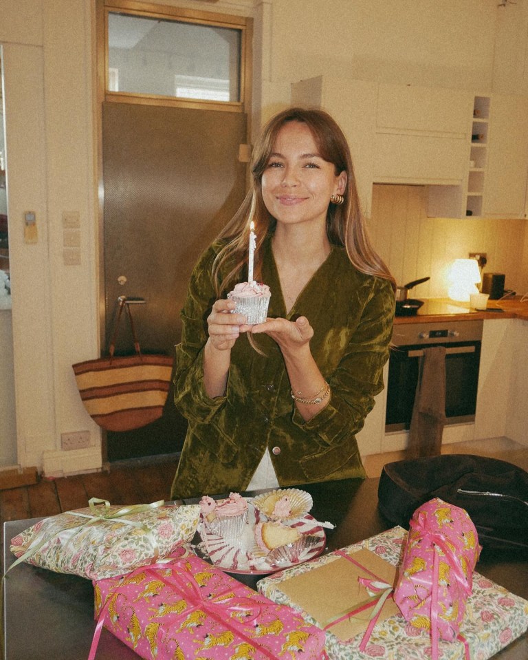 a woman holding a cupcake with a lit candle