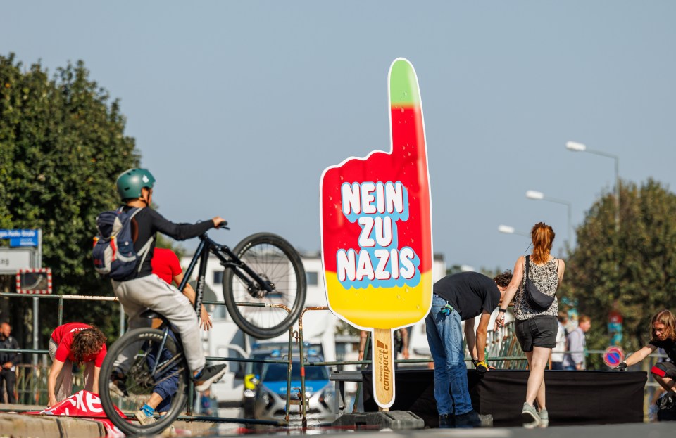 a man riding a bike in front of a sign that says nein zu nazis