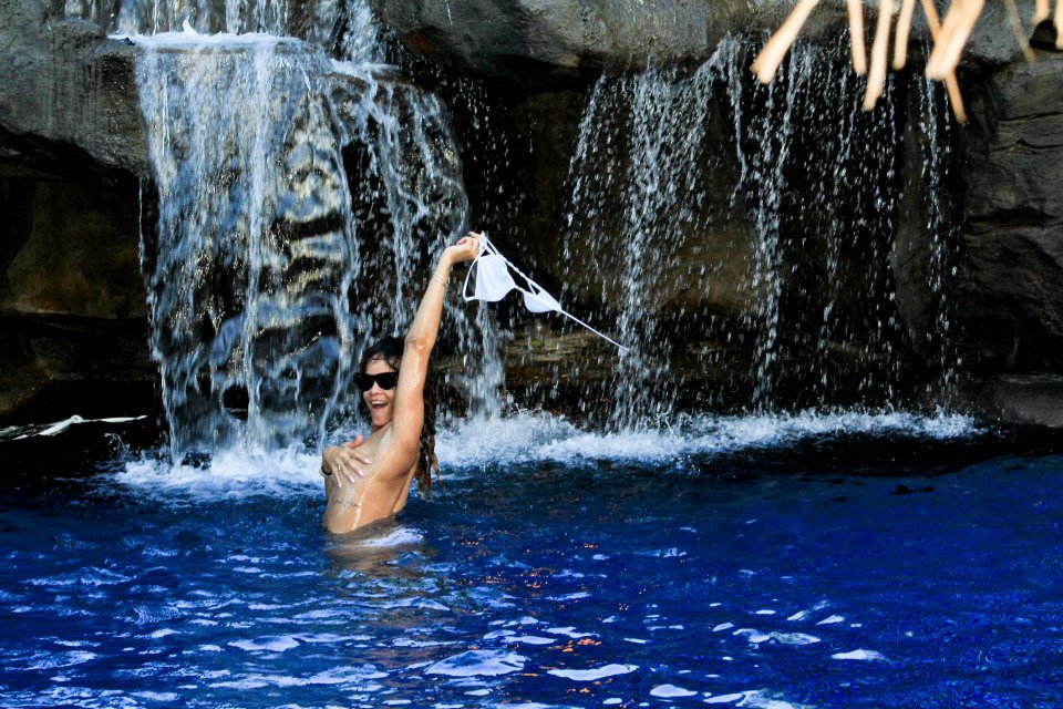 a woman in a bikini is standing in front of a waterfall