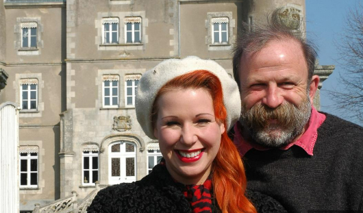 a man and a woman are posing for a picture in front of a building