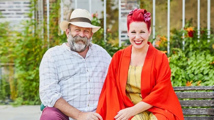 a man and a woman are sitting on a bench in a garden .