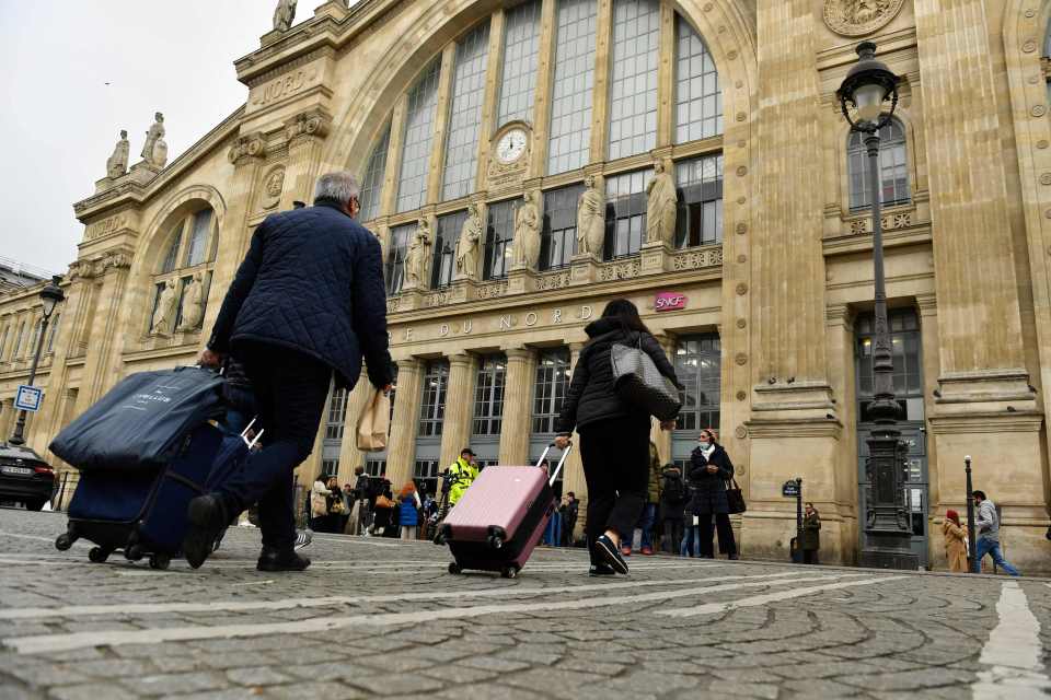 people pulling luggage in front of a building that says sncf