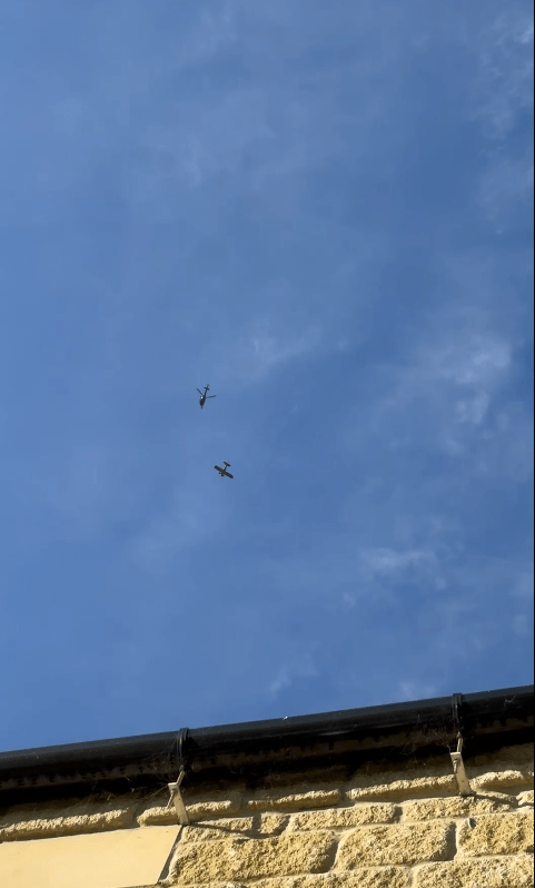 two small planes are flying in the sky above a building