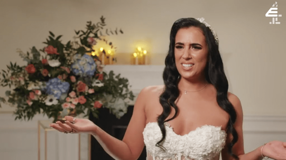 a woman in a wedding dress is standing in front of a bouquet of flowers