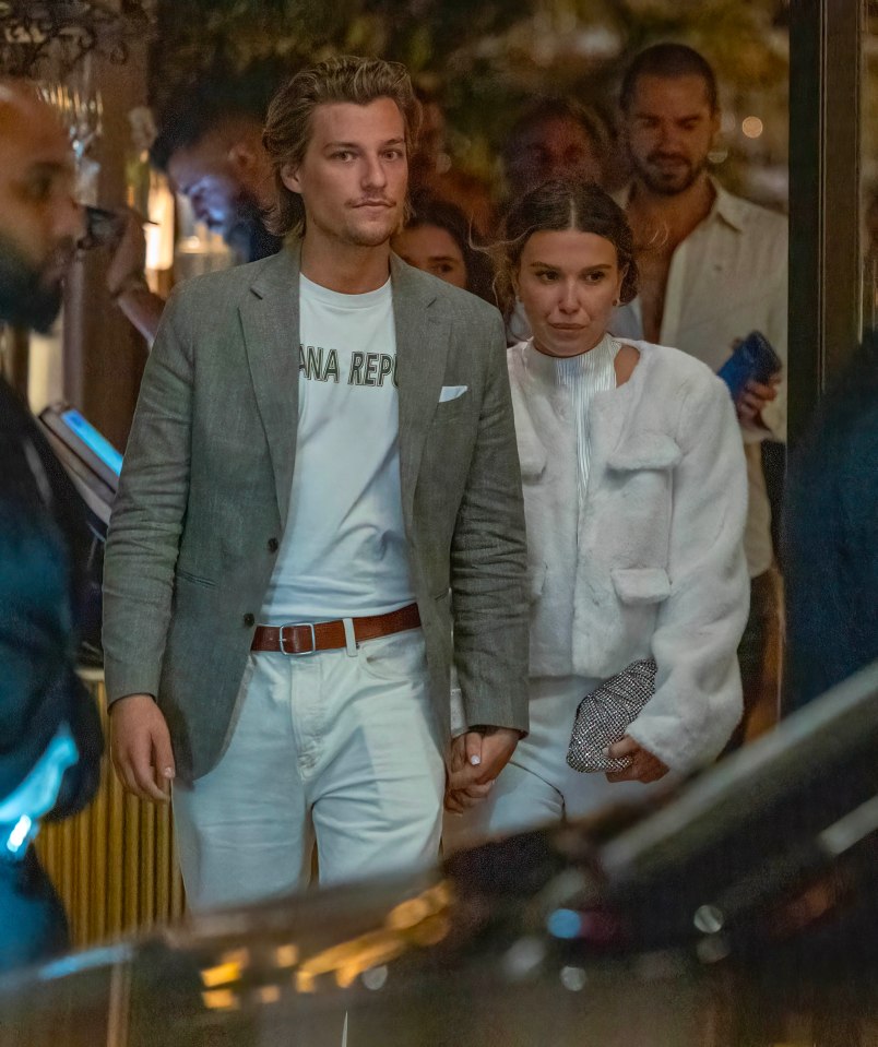 a man wearing a white ana rep t-shirt holds hands with a woman