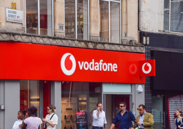 a group of people standing outside of a vodafone store