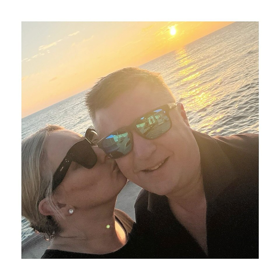 a man and woman wearing sunglasses are kissing in front of the ocean