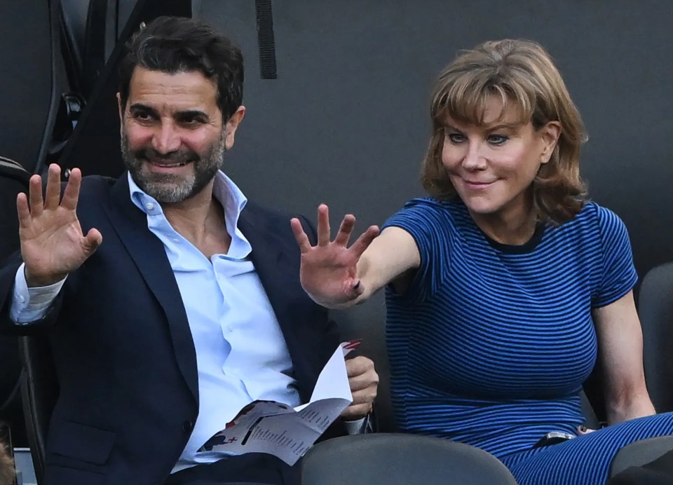 a man in a suit and a woman in a blue dress are sitting in a stadium watching a game