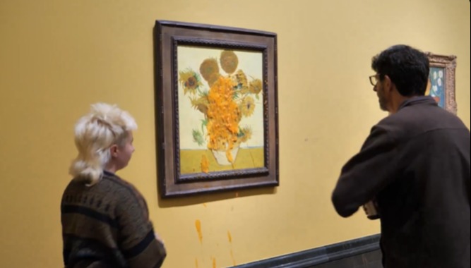 two people looking at a painting of sunflowers on a yellow wall