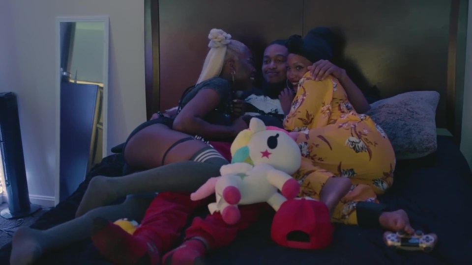 a unicorn stuffed animal sits on a bed with two women