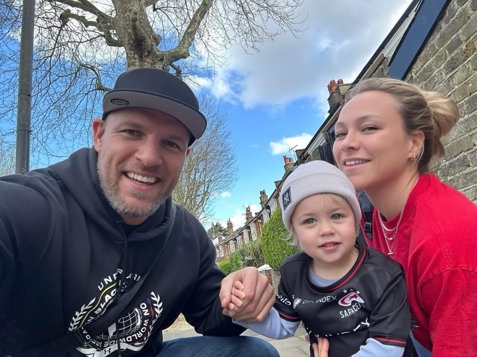 a man and woman are posing with a child who is wearing a shirt that says sharks