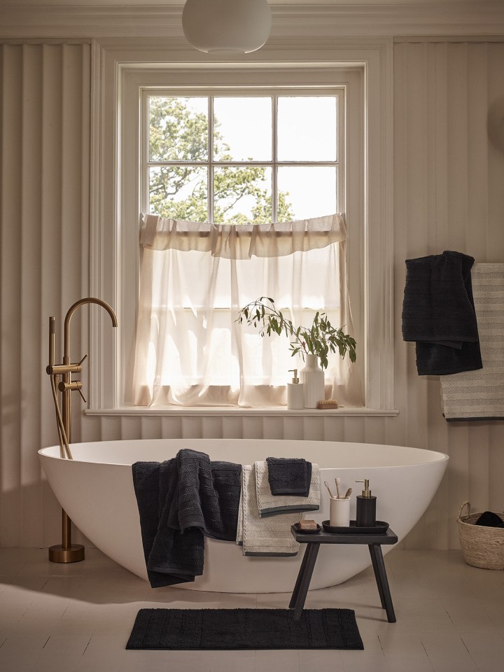 a bathtub in a bathroom with black towels on it