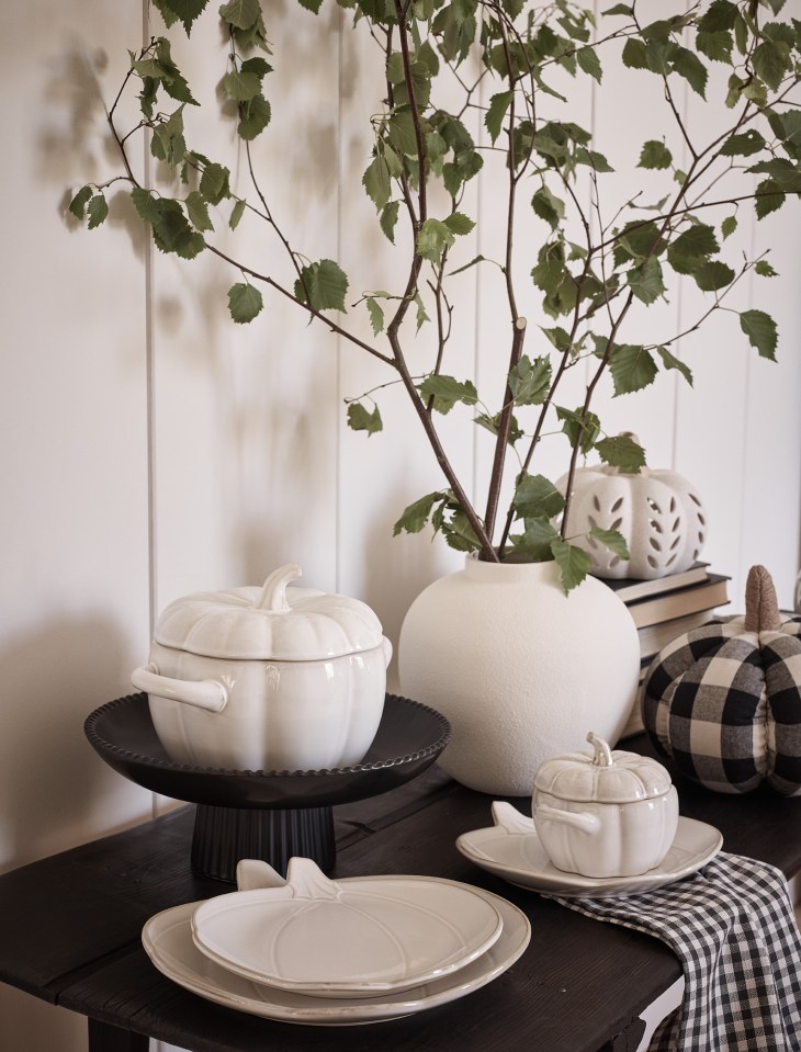 a table with plates bowls and a vase with a plant in it