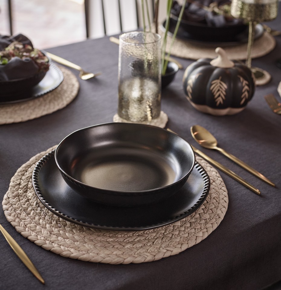 a table setting with black plates and gold silverware