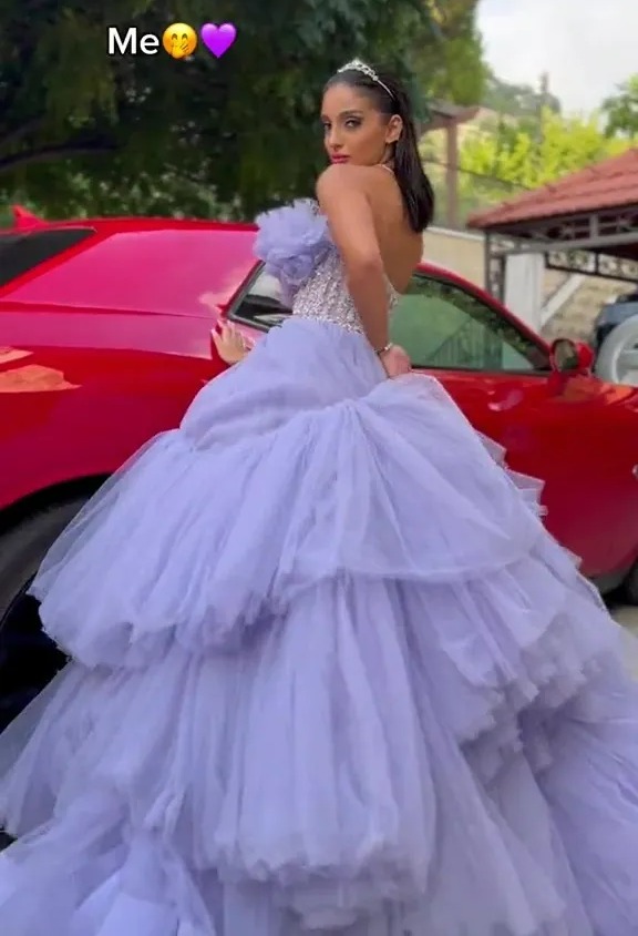 a woman in a purple dress is standing in front of a red car .