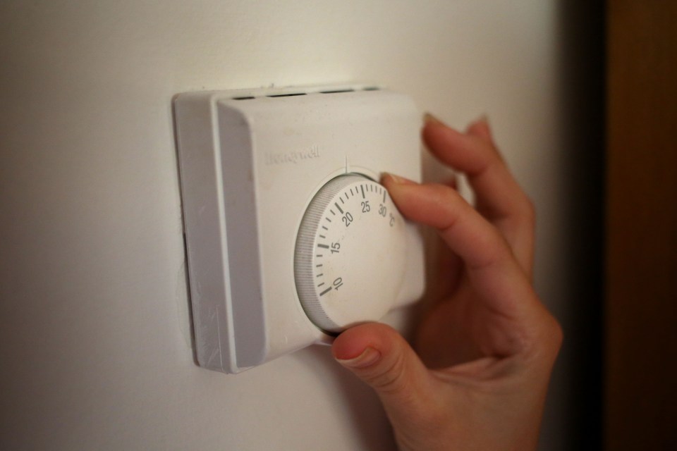 a person is adjusting a honeywell thermostat on a wall