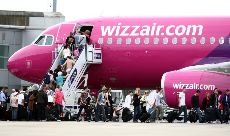 people boarding a pink and purple wizzair plane