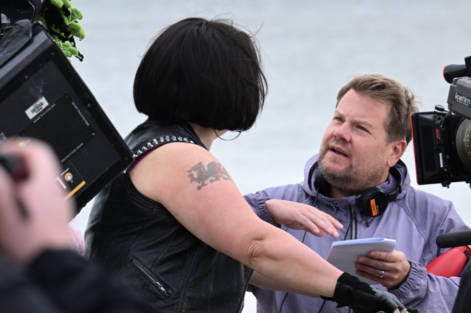 a man in a purple jacket is talking to a woman with a tattoo on her arm