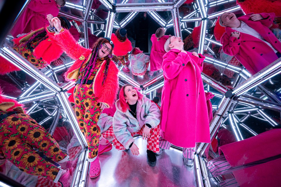 a group of people are standing in a mirrored room