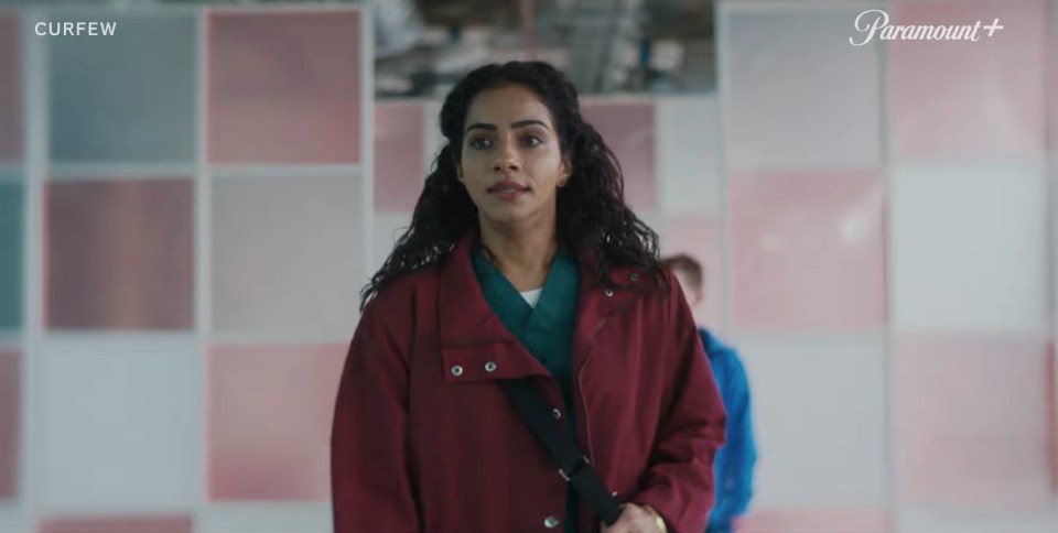 a woman in a red coat stands in front of a wall that says paramount +