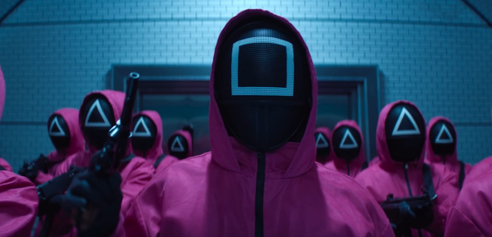 a group of people wearing pink suits and masks with triangles on them