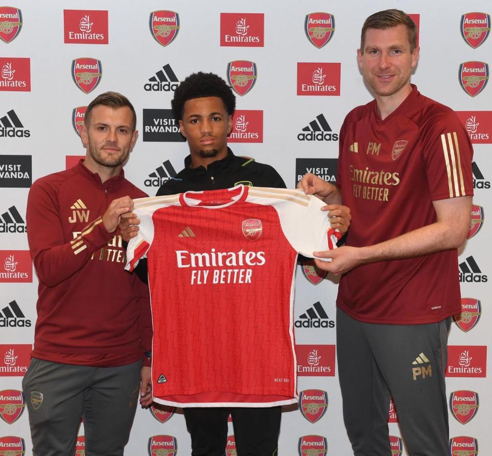 three men holding a red emirates fly better jersey