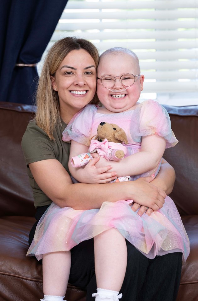 a woman is holding a little girl who is wearing glasses and a pink dress