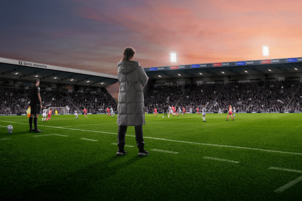 a woman watches a soccer game in a sports interactive stadium