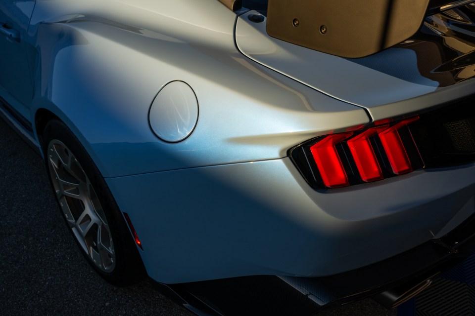 a close up of a silver car with a red tail light