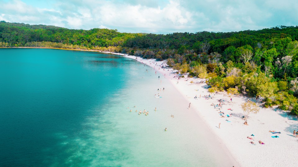 an aerial view of a beach with a lake in the background