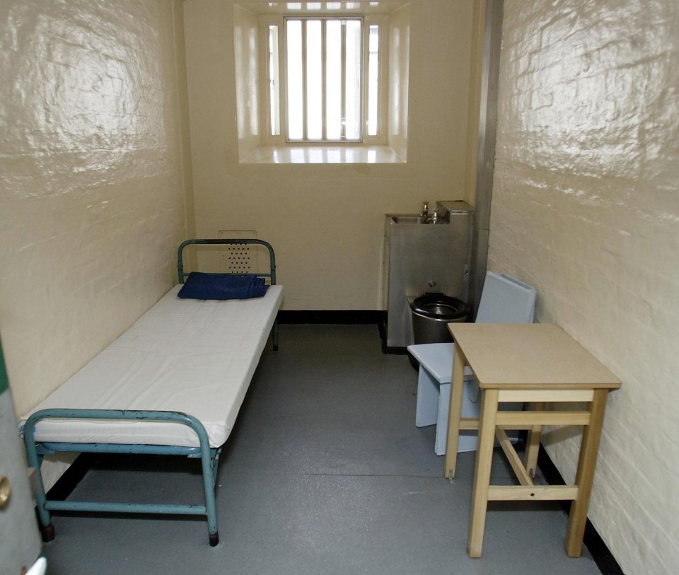 a prison cell with a bed and a small table