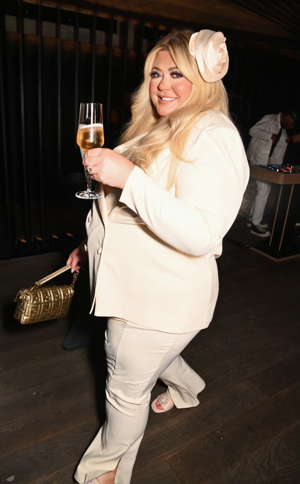 a woman in a white suit is holding a glass of wine