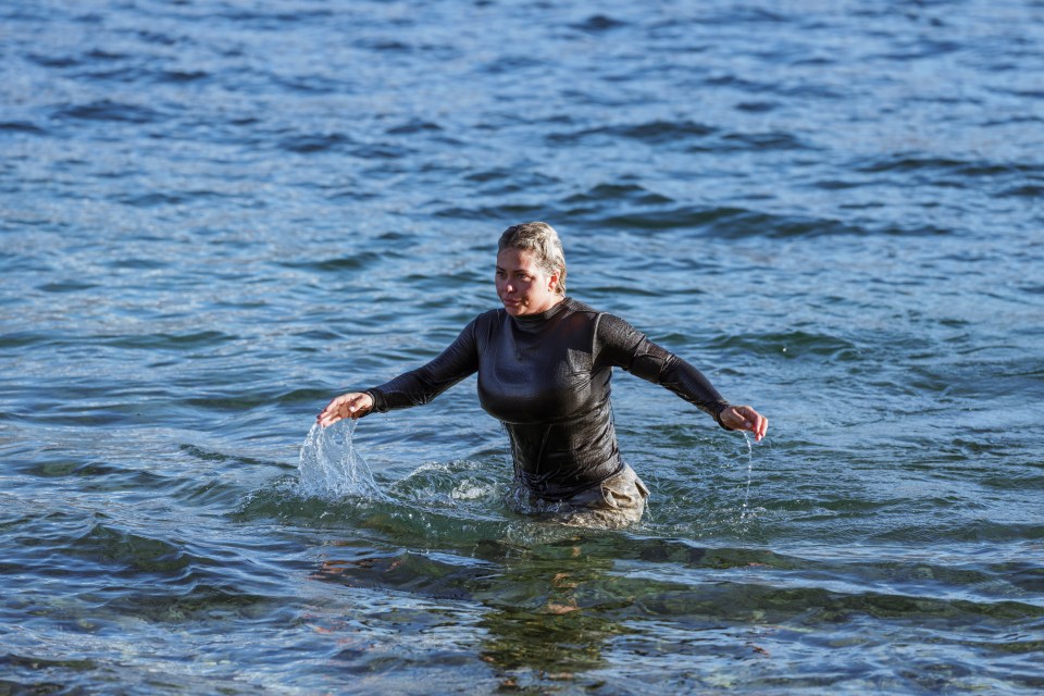 a woman in a wet suit is walking out of the water