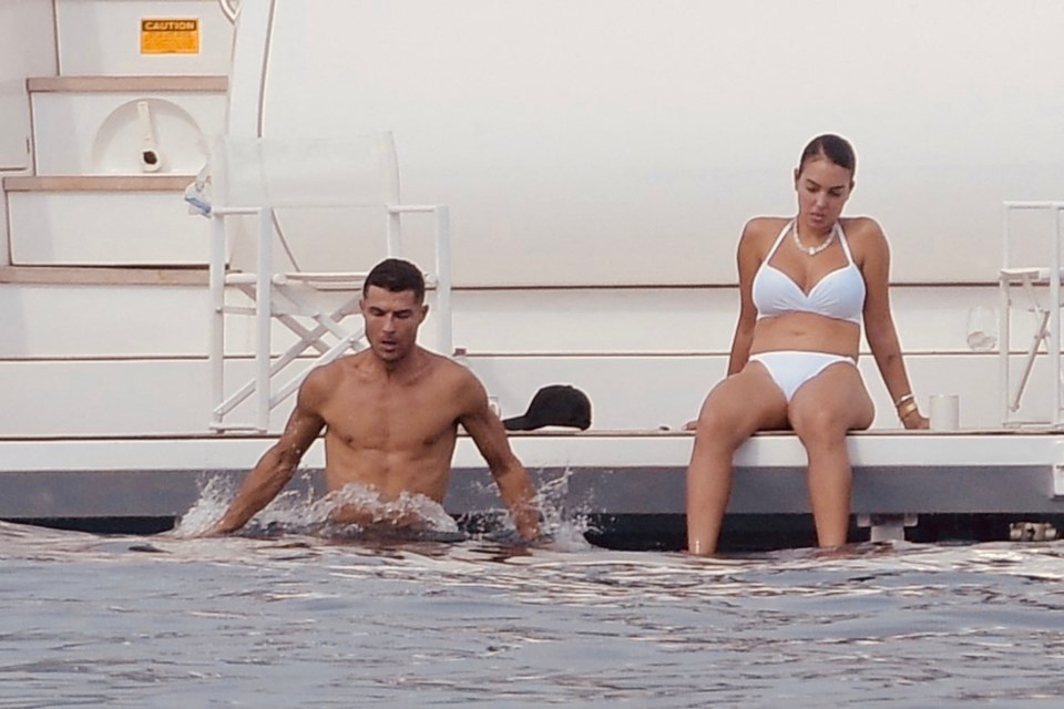 a woman in a bikini sits next to a man in the water