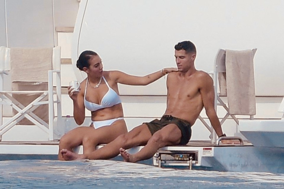 a man without a shirt sits next to a woman in a white bikini