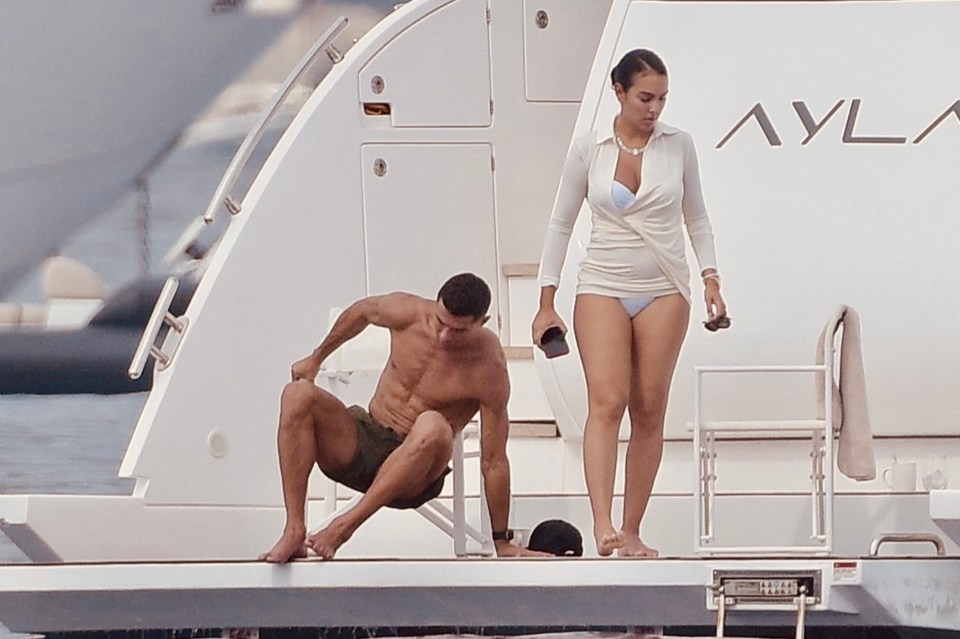 a woman in a bikini stands next to a shirtless man on a boat that says ayl