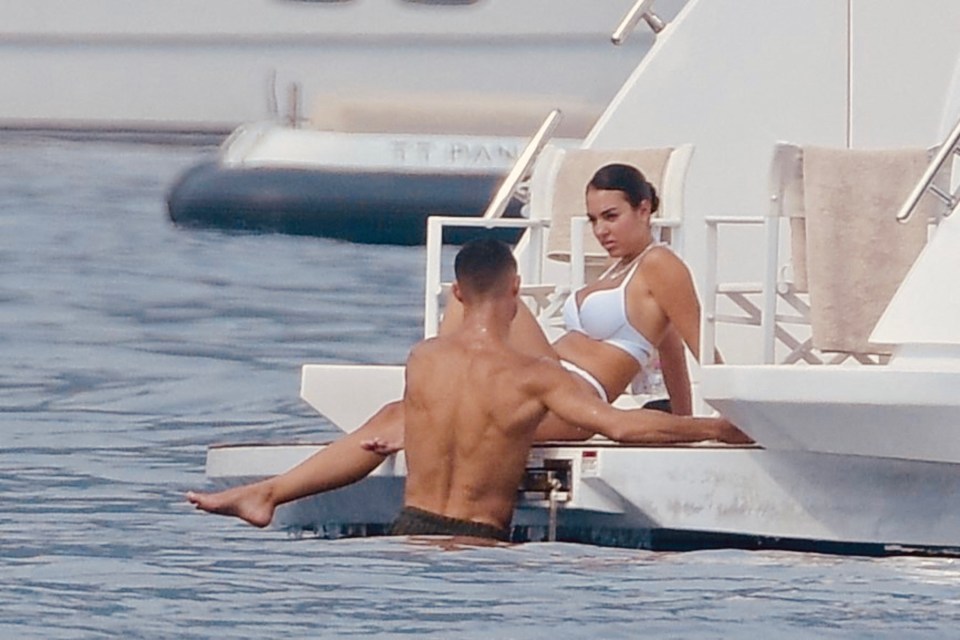 a woman in a bikini sits on a man 's lap in the water near a titan boat