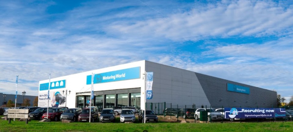 a motoring world dealership with cars parked in front of it