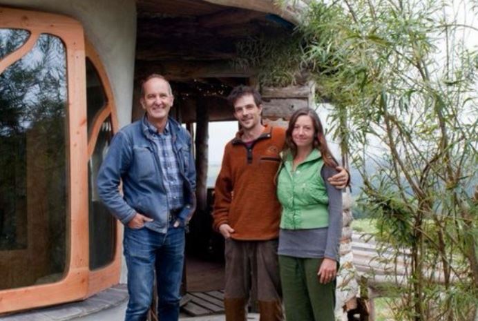 three people posing for a picture in front of a house