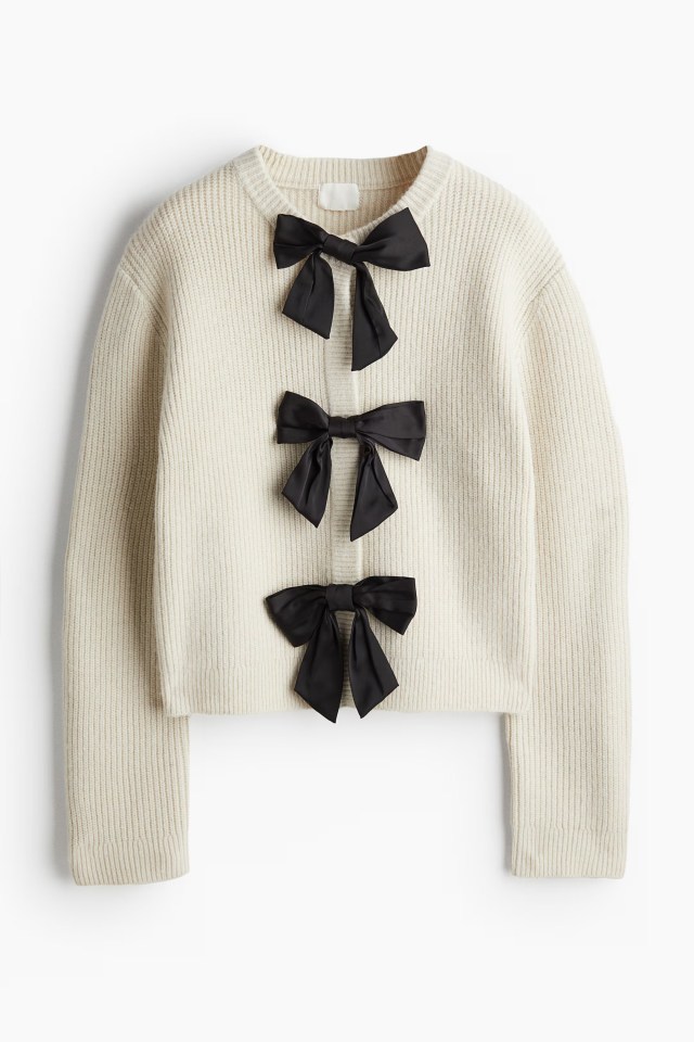 a white sweater with black bows on the front